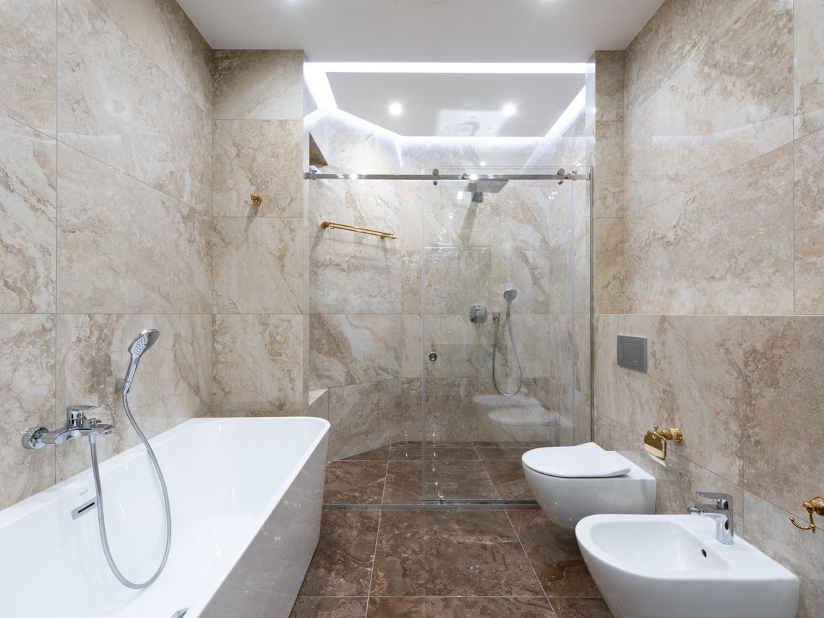 Travertine-tiled bathroom with a walk-in shower and freestanding bath