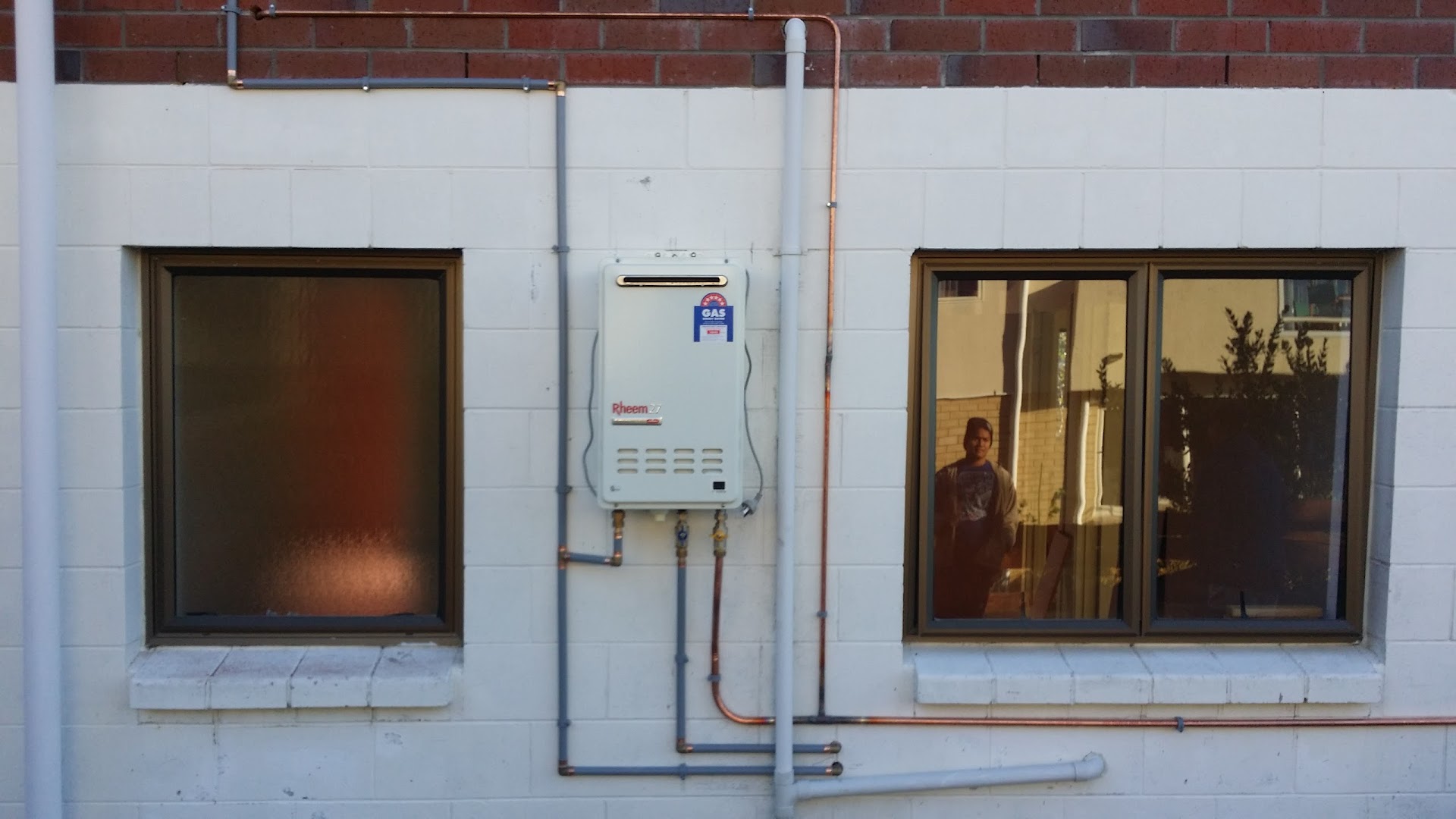 Rheem gas water heater installed on exterior wall with copper gas lines