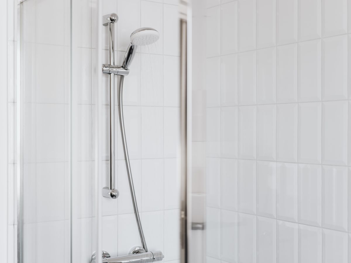 Chrome shower fittings in a clean white-tiled bathroom