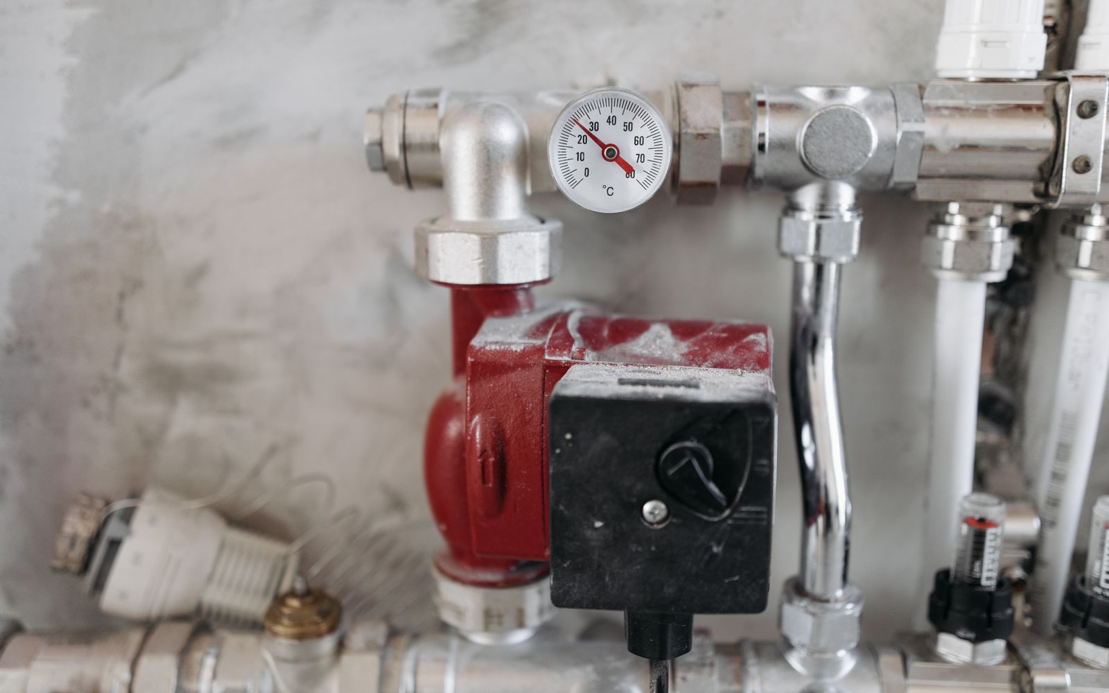 Chrome plumbing manifold with a temperature gauge and copper pipework